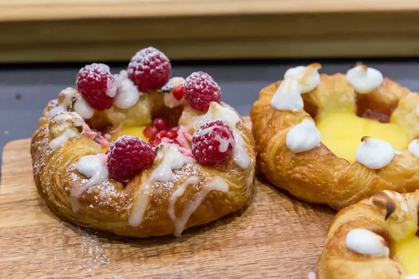 Puddingplunder mit Himbeeren und Zuckerguss auf einem Holzbrett