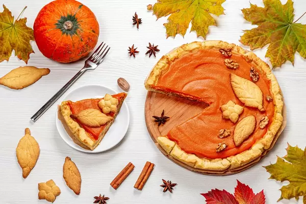 Pumpkin pie with autumn decorations on white wooden table. Top view (Flip 2019)