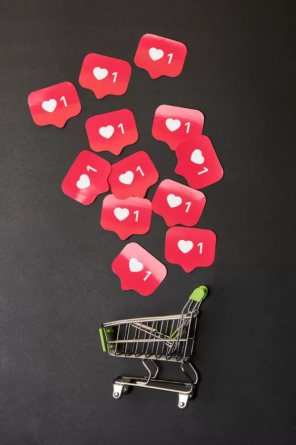Purchasing paid promotion - shopping trolly and pile of Instagram love icons