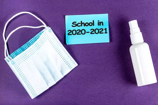 Purple background with medical mask and antiseptic. School concept