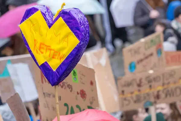 Purple-yellow heart with "Save the climate!" text and other signs in the background