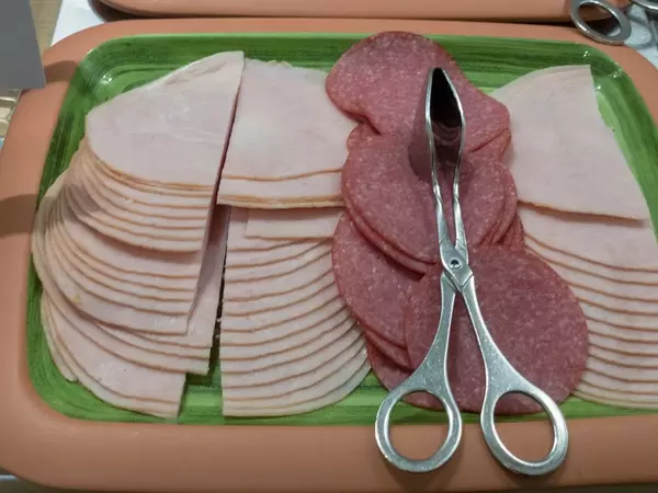 Putenschinken und Putensalami mit Zange zum servieren an einem Buffet