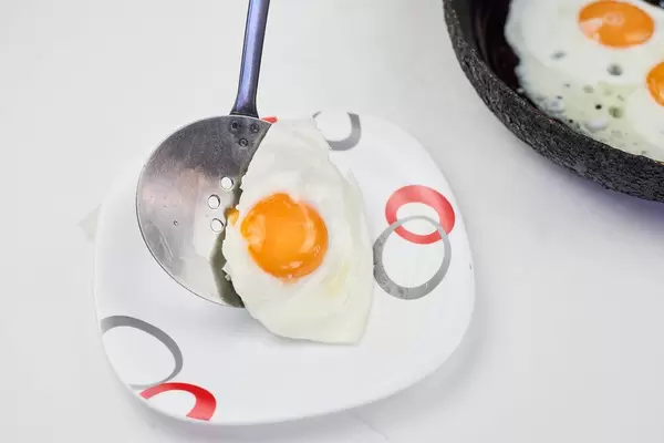 Putting a freshly fried sunny-up-side egg on the plate