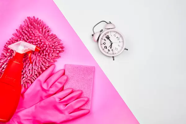Putzen verschoben? Es ist nie zu Spät. Rosa und rote Reinigungsprodukte, Wecker und Platz für Text