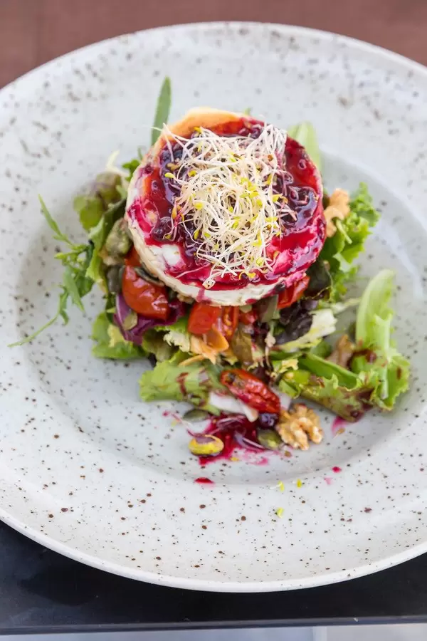 Q11, Pollença: gegrillter Ziegenkäse mit getrockneten Tomaten, Salat, Sprossen, rotem Beerendressing