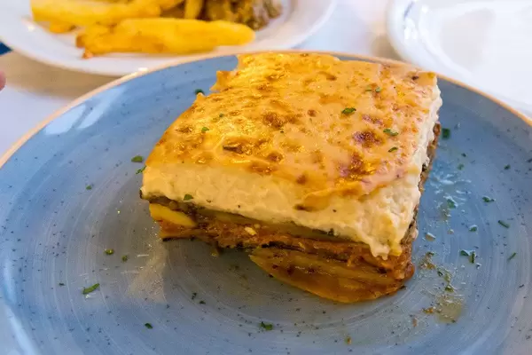 Quadratisches Stück Lasagne, auf einem blauen Teller