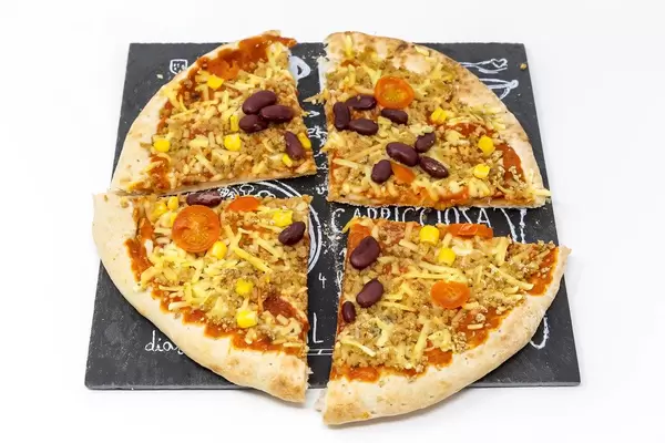 Quartered meatless California pizza with red beans and corn on black stone plate