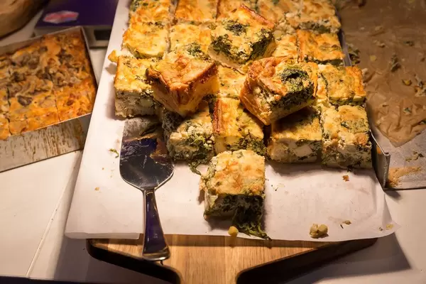 Quiche mit grünem Gemüse, Brokkoli, Spinat und Bergkäse in kleinen Stücken geschnitten
