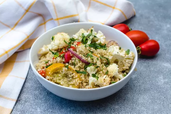 Quinoa mit geröstetem Gemüse wie Blumenkohl, in einer weißen Schale