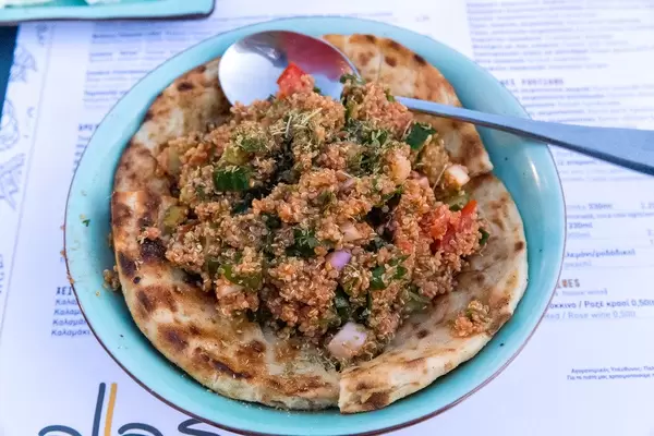 Quinoa-Tamboule mit frischen Tomaten aus Paros, Zwiebeln, Petersilie und Olivenöl auf Fladenbrot