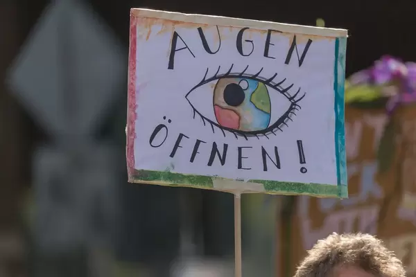 "Augen öffnen!" - Demonstrationsschild fordert mehr Achtsamkeit und Umweltbewusstsein für die Erde