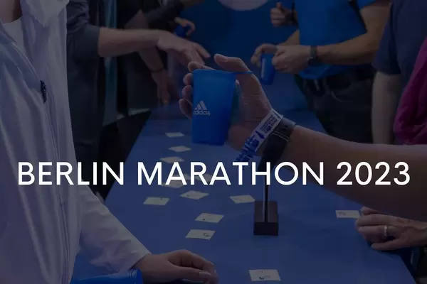 "Berlin Marathon 2023" -Bildtite, vor Sportlern am blauen Adidas-Infostand