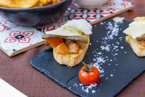 "Fusion" bruschetta with chopped tomatoes, pickled aubergine, pistachio pesto and garlic. Q11 in Pollença