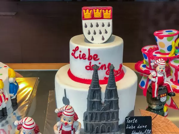 "Love your city / Liebe deine Stadt": cake celebrating the city of Cologne with the cathedral and the emblem of the city, surrounded by typical decoration of the city's carnival
