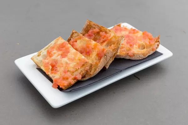 "Pan de cristal con tomate" ist ein dünnes Brot mit Tomatenaufstrich im Restaurant des Hotel 1898, auf einem weißen Teller in Barcelona, Spanien