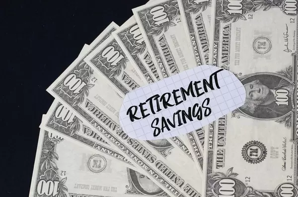"Retirement savings" Text auf kariertem Zettel mit 100-Dollar-Scheinen