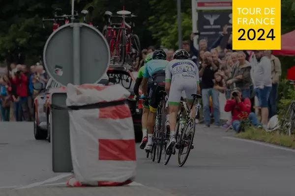 Racing cyclists at the bicycle race with a team car on the road and the text "Tour de France 2024".
