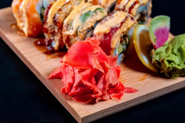 Rainbow dragon sushi set with ginger, lemon and wasabi on wooden Board