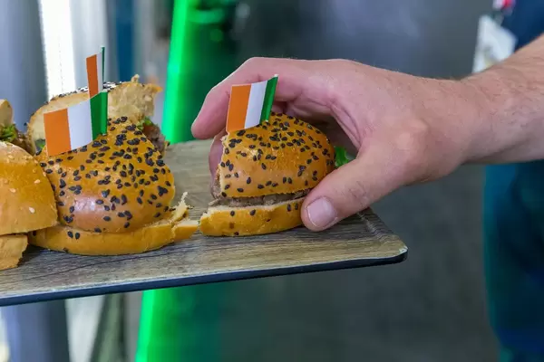 Rangeland foods - Hand greift ein Burgerstück von einem Probiertablet