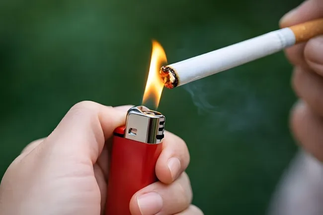 Raucher zündet Zigarette mit Feuerzeug an