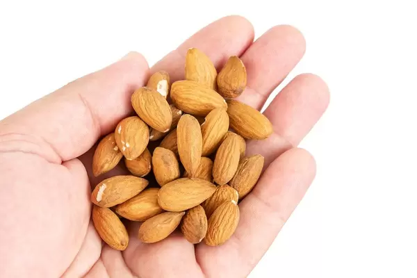 Raw Almonds in the hand above white background