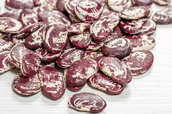 Raw big beans on a white wooden background