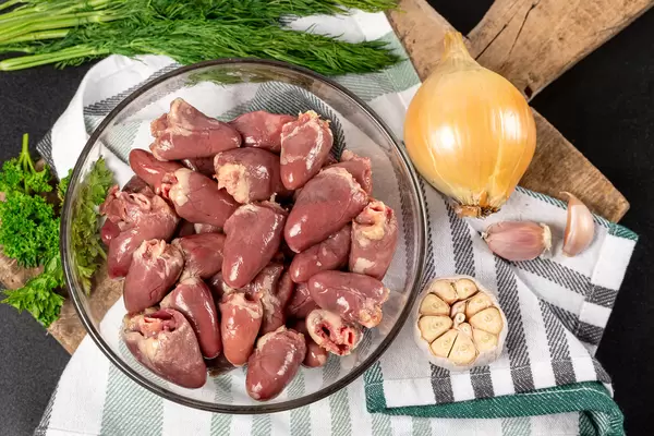 Raw bird hearts with herbs, onions and garlic, top view