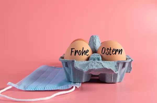Raw brown eggs in egg box with Frohe Ostern text