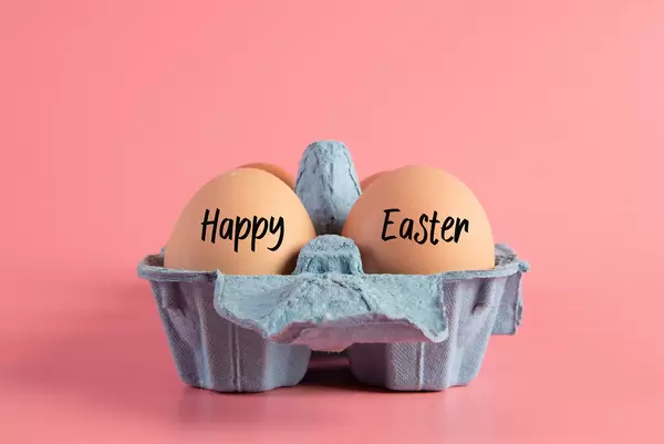 Raw brown eggs in egg box with Happy Easter text