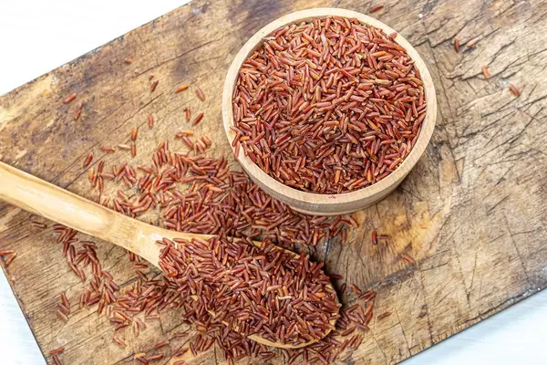 Raw brown rice in a wooden bowl and spoon on an old kitchen Board. The view from the top (Flip 2019)