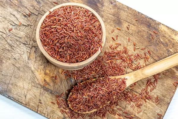 Raw brown rice in a wooden bowl and spoon on an old kitchen Board. The view from the top