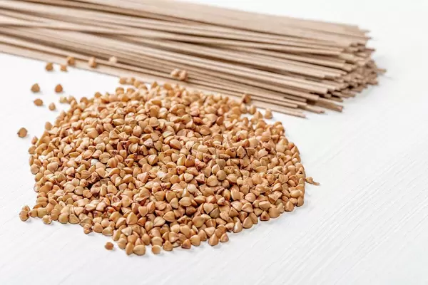 Raw buckwheat and buckwheat soba noodles on white wooden background (Flip 2019)