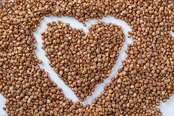 Raw buckwheat on the table in the shape of a heart