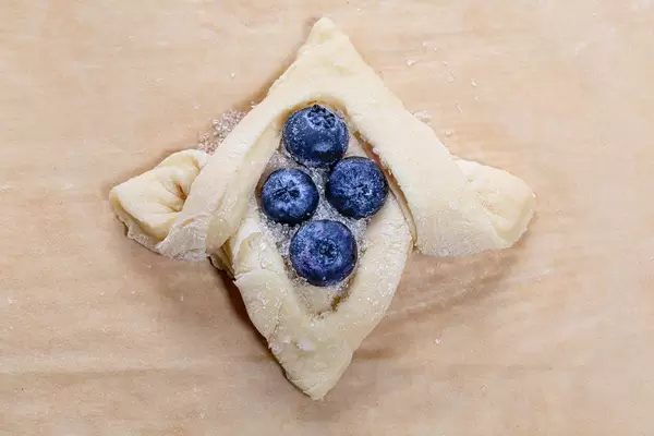 Raw bun with sugar and blueberries