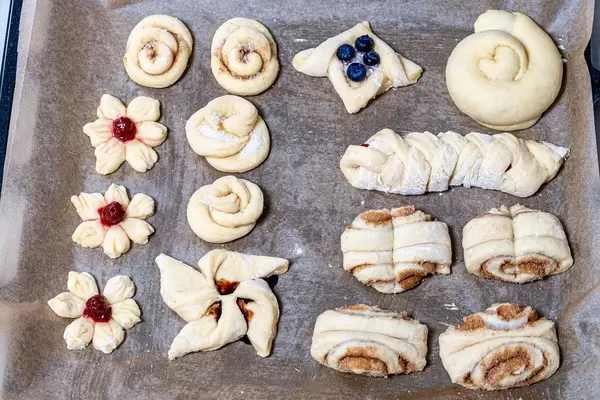 Raw buns on a baking sheet with different fillings and different shapes. Top view (Flip 2019)
