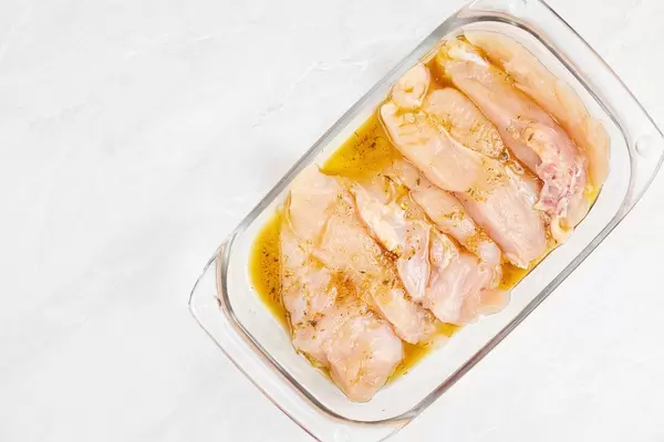 Raw Chicken Breasts marinated in the glass pan