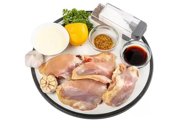 Raw chicken pieces with ingredients for cooking