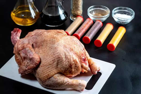 Raw chicken with ingredients on black background