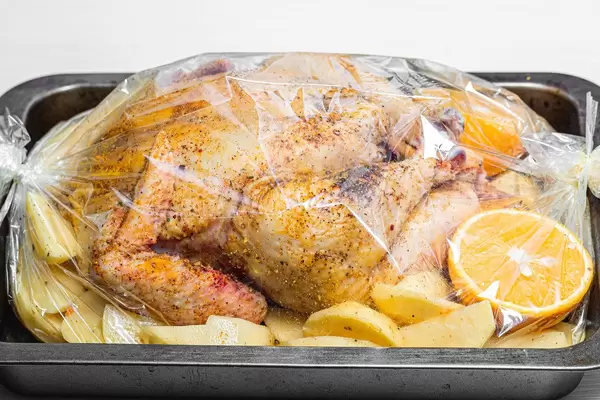 Raw chicken with spices, potatoes and oranges in a baking tray before baking