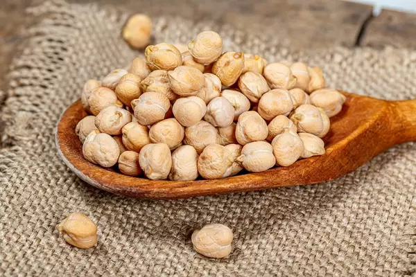 Raw chickpeas grain in a wooden spoon on burlap