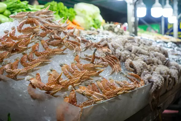 Raw Crab Legs and Baby Octopus on Crushed Ice with Lettuce and Cabbage in the Background at a Barbecue Street Food Vendor in the City Center of Can Tho, Vietnam