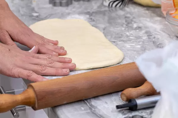Raw Dough on the table with hands on it and rolling pin
