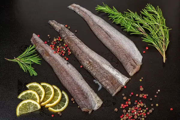 Raw fish fillet with spices on a black background, top view