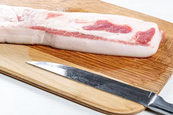 Raw lard with a knife on the kitchen Board