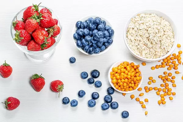 Raw oatmeal with fresh berries and almonds on a white wooden background