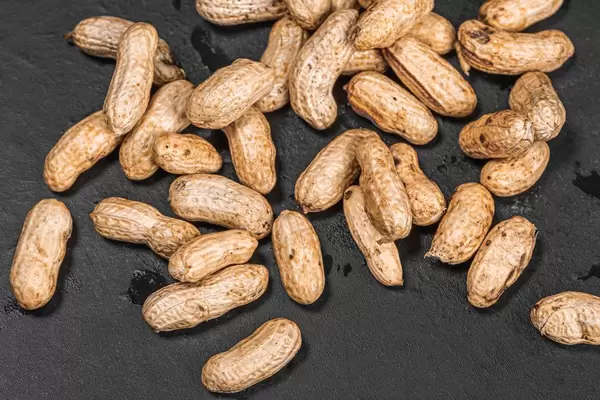 Raw peanuts on black background with peel