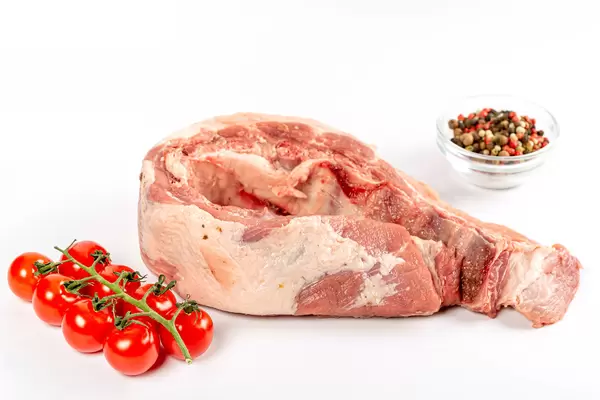 Raw pork ribs with cherry tomatoes and a mix of peppers on white