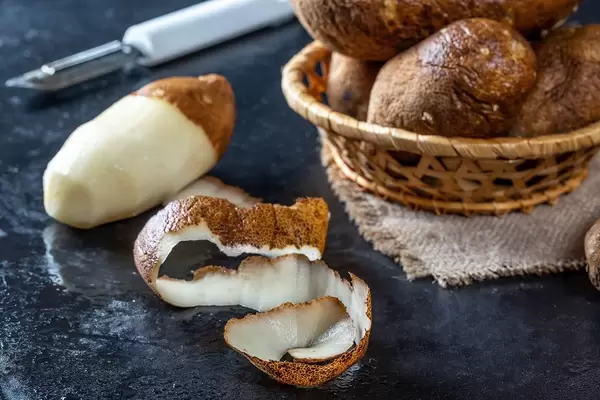 Raw potatoes and a knife for cleaning vegetables on a black background