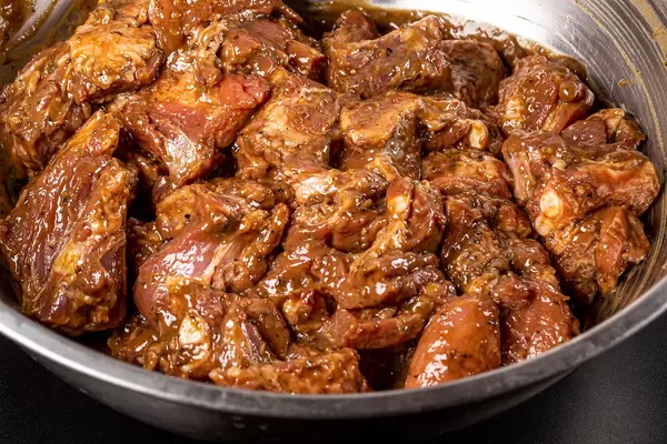 Raw ribs with spices and marinade in a metal bowl