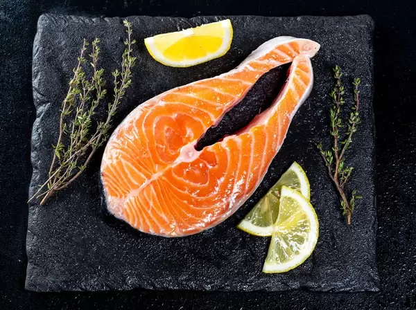 Raw salmon fillets on dark background